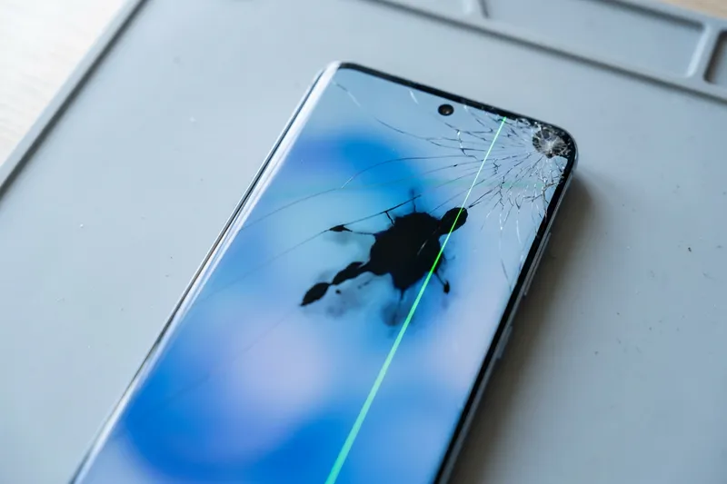 Smartphone with cracked glass, a black spot and a green line on the screen